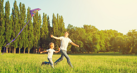 Dad and son child flying a kite in summer nature